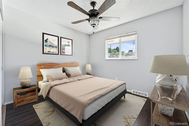 bedroom featuring ceiling fan, a textured ceiling, and dark wood-type flooring