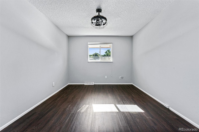 spare room with a textured ceiling and dark hardwood / wood-style flooring