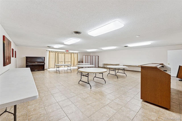 recreation room featuring a textured ceiling and light tile patterned floors