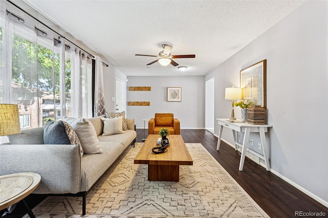 living room with ceiling fan, dark hardwood / wood-style floors, and a textured ceiling