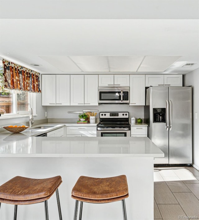 kitchen featuring appliances with stainless steel finishes, white cabinetry, and a kitchen breakfast bar