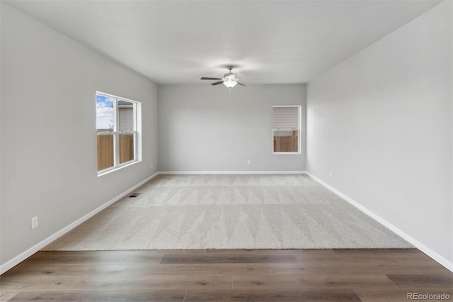 unfurnished room with wood finished floors, visible vents, baseboards, and ceiling fan