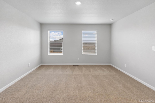 empty room featuring light colored carpet and baseboards