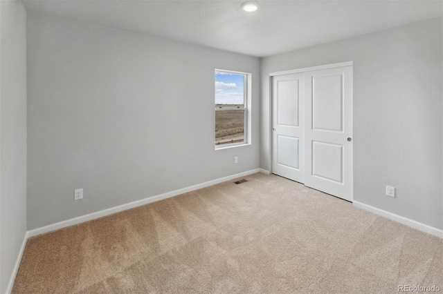 unfurnished bedroom with a closet, visible vents, baseboards, and carpet floors