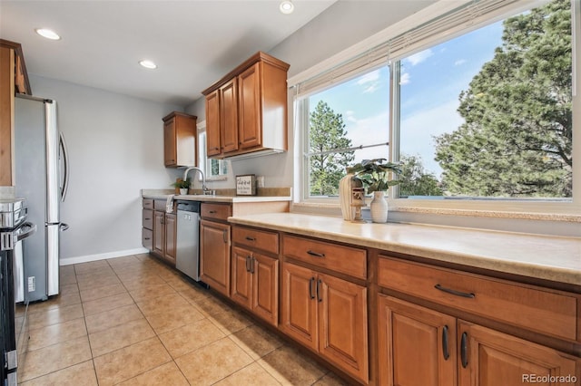4231 W Ponds Cir, Littleton, CO 80123 - kitchen with appliances with stainless steel finishes, light countertops, brown cabinetry, recessed lighting, and light tile patterned floors
