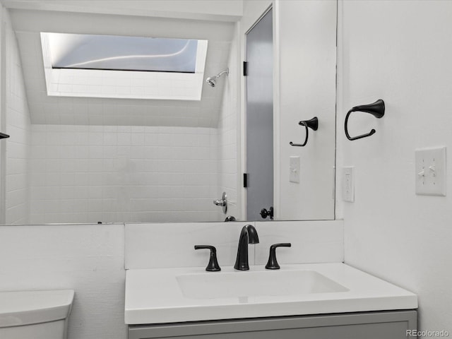 bathroom with vanity, toilet, and tiled shower