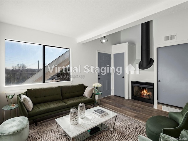 living room featuring a fireplace, beam ceiling, and dark wood-type flooring