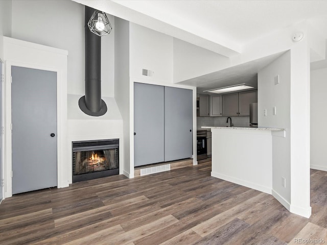 unfurnished living room featuring a high ceiling, dark hardwood / wood-style flooring, and sink