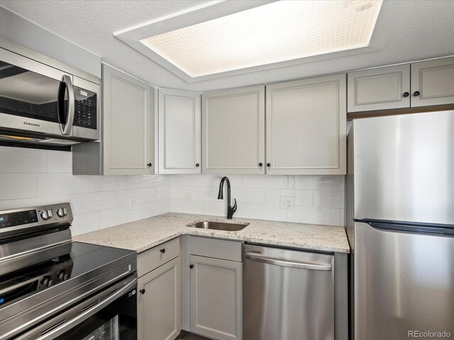 kitchen with backsplash, gray cabinetry, sink, and appliances with stainless steel finishes