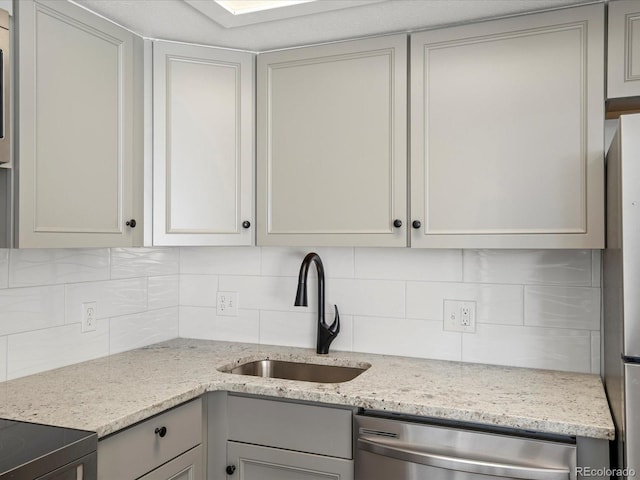 kitchen with decorative backsplash, light stone countertops, sink, and appliances with stainless steel finishes