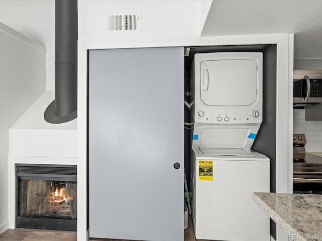 laundry room with wood-type flooring and stacked washer / dryer