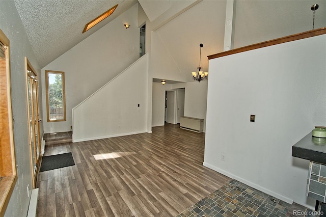 unfurnished living room with dark hardwood / wood-style flooring, high vaulted ceiling, a textured ceiling, and a notable chandelier