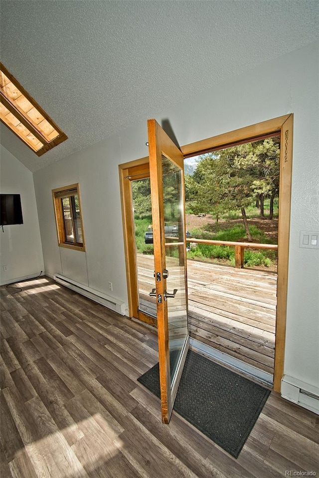 entryway with dark hardwood / wood-style flooring, a textured ceiling, a baseboard heating unit, and vaulted ceiling with skylight