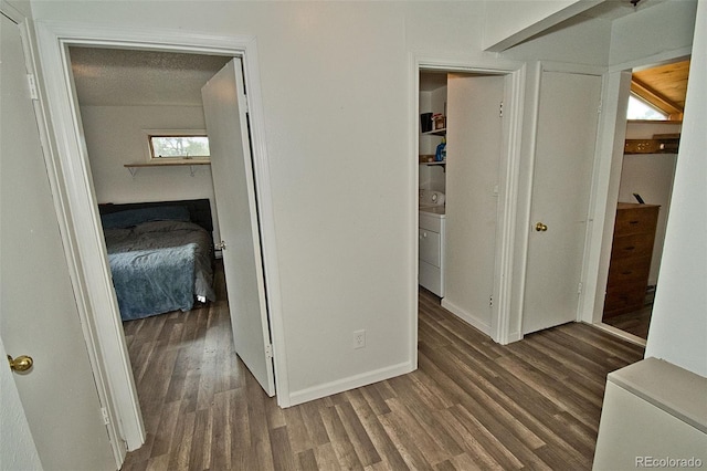 corridor featuring a textured ceiling, dark hardwood / wood-style flooring, and washer / dryer