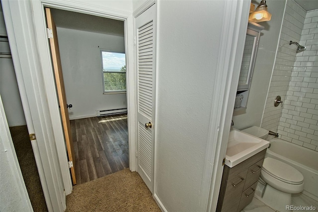 full bathroom featuring a baseboard heating unit, vanity, tiled shower / bath combo, and toilet