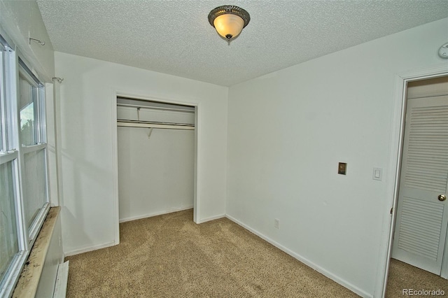 unfurnished bedroom with light carpet, a textured ceiling, and a closet