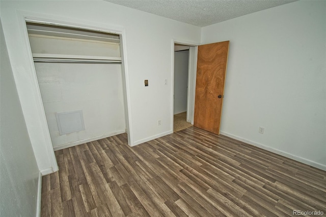 unfurnished bedroom with dark hardwood / wood-style flooring, a closet, and a textured ceiling