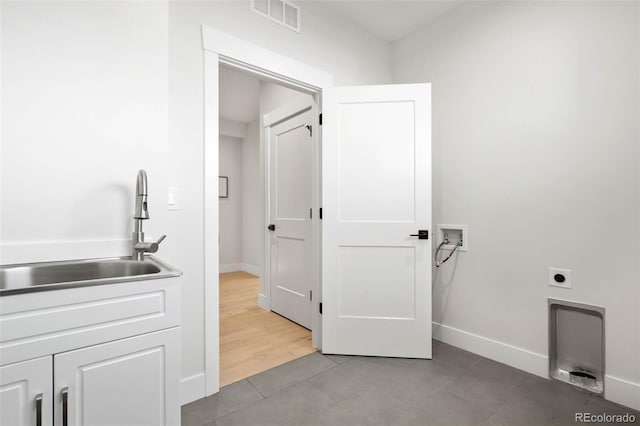 washroom featuring electric dryer hookup, visible vents, washer hookup, a sink, and baseboards