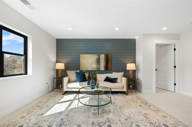 living room with recessed lighting, visible vents, and wooden walls