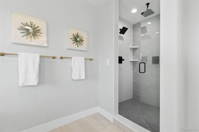 bathroom featuring recessed lighting, baseboards, wood finished floors, and a tile shower