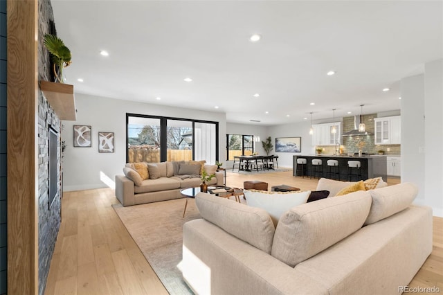 living room with light wood finished floors, recessed lighting, and baseboards