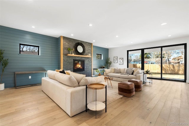 living room with recessed lighting, an accent wall, a fireplace, and light wood finished floors