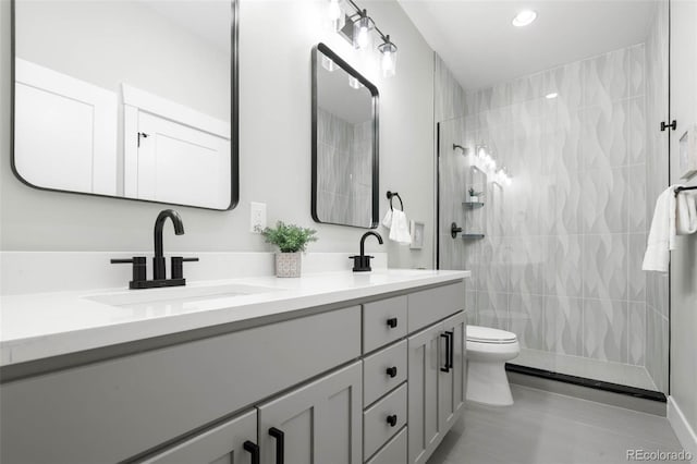 bathroom with double vanity, tiled shower, toilet, and a sink