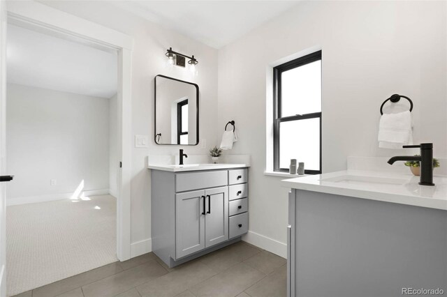 full bathroom featuring a sink, baseboards, two vanities, and tile patterned floors