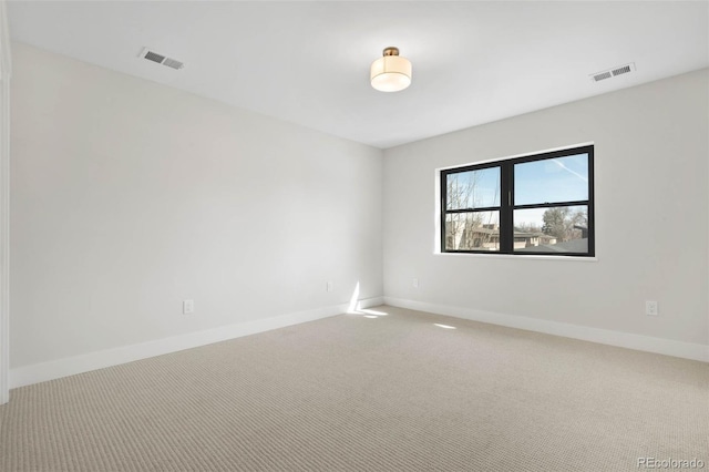 unfurnished room with carpet, visible vents, and baseboards