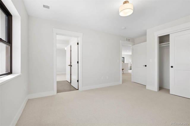 unfurnished bedroom with a closet, visible vents, baseboards, and carpet