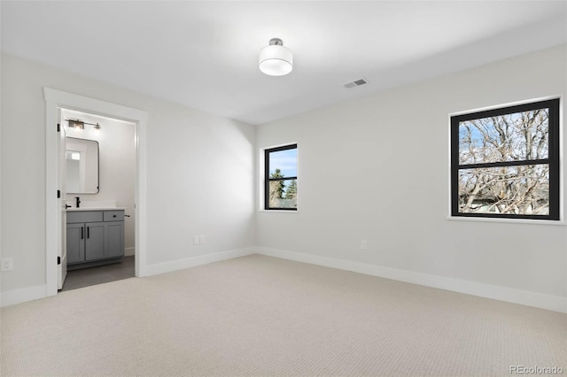 unfurnished bedroom featuring visible vents, a sink, baseboards, and carpet floors