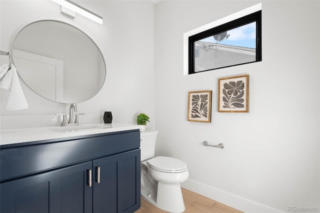 bathroom with baseboards, wood finished floors, toilet, and vanity
