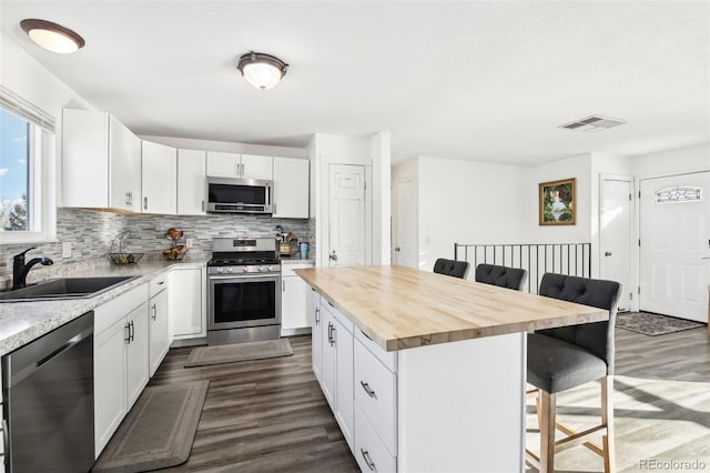 kitchen featuring white cabinetry, butcher block counters, a kitchen breakfast bar, stainless steel appliances, and a center island