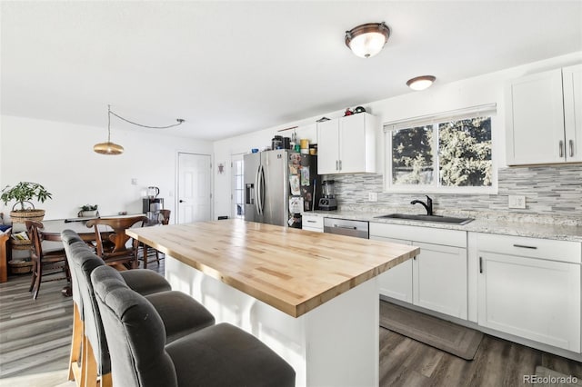 kitchen with sink, white cabinetry, stainless steel appliances, light stone counters, and decorative backsplash