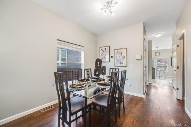 dining space with dark wood-style floors, baseboards, visible vents, and a notable chandelier