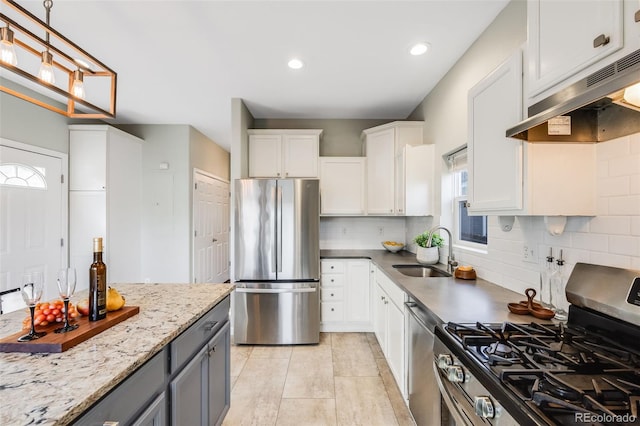 kitchen with decorative backsplash, appliances with stainless steel finishes, under cabinet range hood, white cabinetry, and a sink