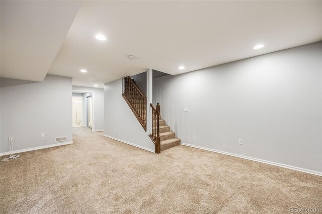 finished below grade area with recessed lighting, light colored carpet, visible vents, stairway, and baseboards