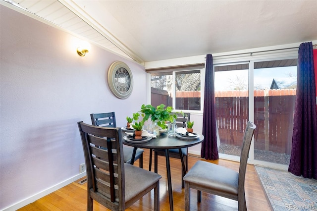 dining room with lofted ceiling, wood finished floors, and baseboards