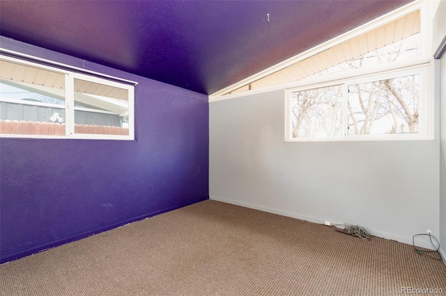 carpeted spare room with vaulted ceiling