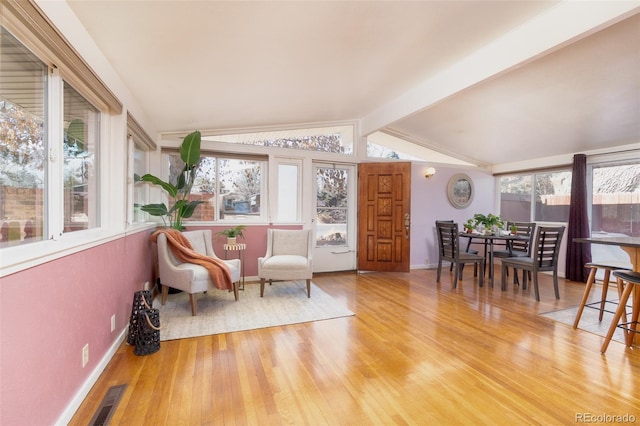 living area featuring lofted ceiling with beams, visible vents, baseboards, and wood finished floors