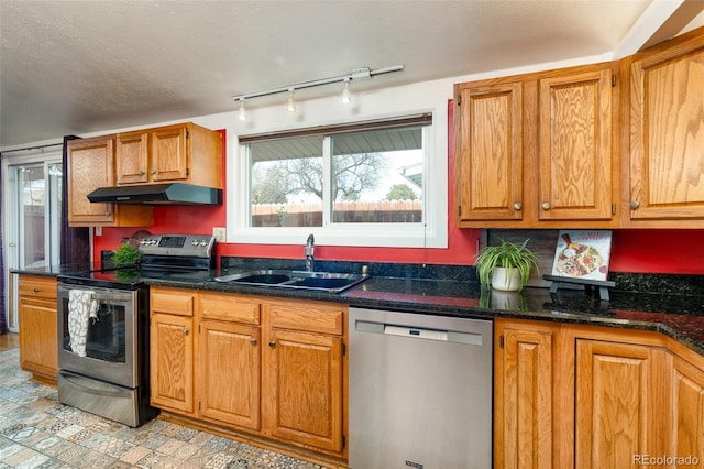 2370 S Meade St, Denver, CO 80219 - kitchen with stainless steel appliances, under cabinet range hood, a sink, track lighting, and brown cabinetry