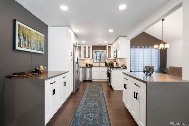 kitchen featuring glass insert cabinets, appliances with stainless steel finishes, dark wood finished floors, and hanging light fixtures