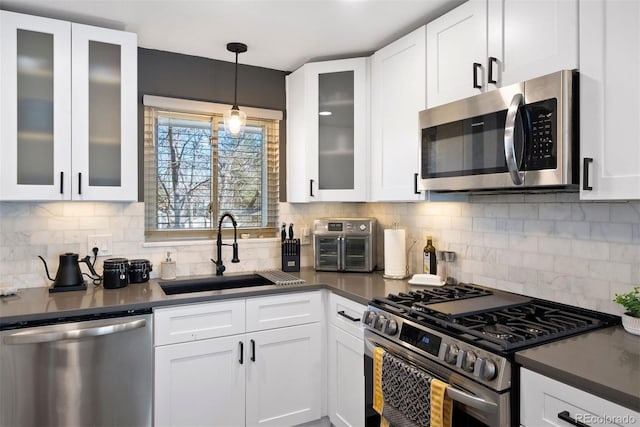 kitchen featuring a sink, stainless steel appliances, dark countertops, and white cabinets