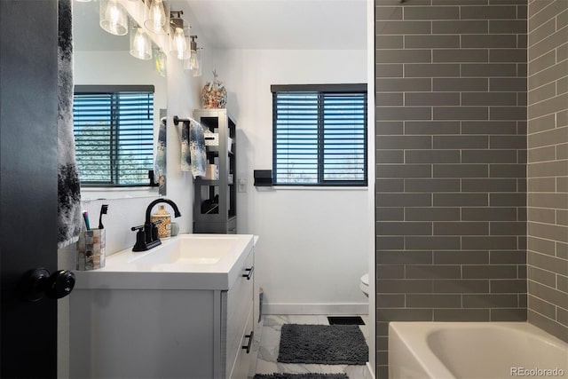 bathroom with toilet, vanity, baseboards, and washtub / shower combination