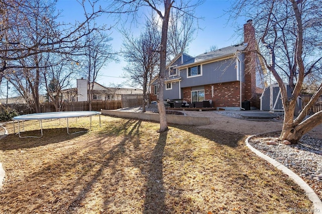 rear view of property with an outbuilding, a patio, a storage unit, and a trampoline