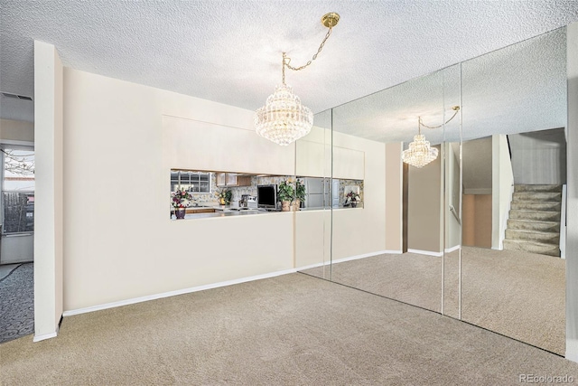 interior space with carpet floors, a textured ceiling, and a notable chandelier