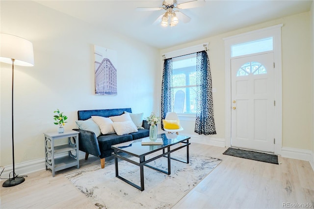 living area with baseboards, wood finished floors, and ceiling fan