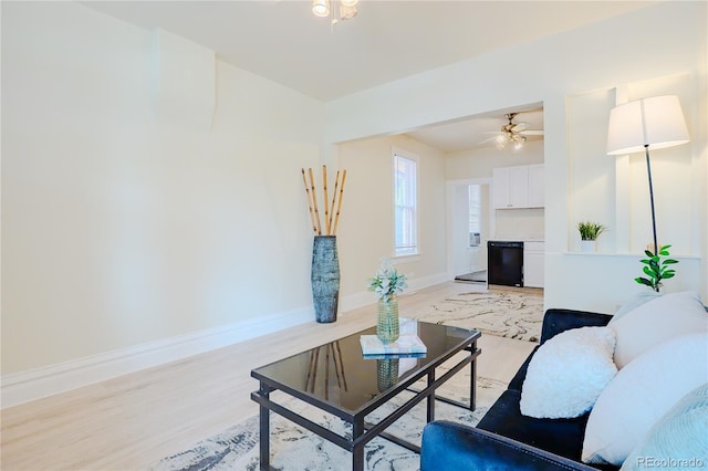 living area featuring a ceiling fan, light wood-style flooring, and baseboards