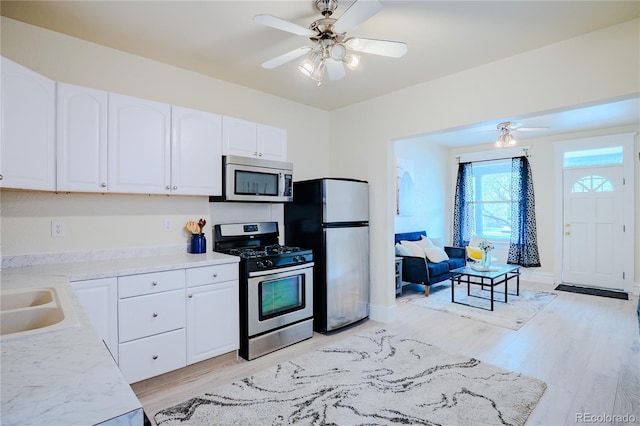 kitchen with white cabinetry, light wood-type flooring, ceiling fan, and appliances with stainless steel finishes