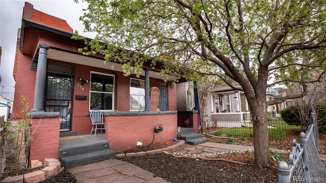 view of front of property featuring covered porch, fence, and brick siding